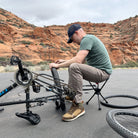 Man working on bike in the desert while sitting on stool