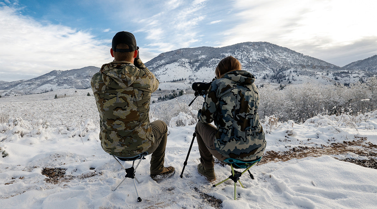 man and woman hunters glassing on compass 360 stool scope wildlife in mountains moose bear elk deer bull buck camoflauge