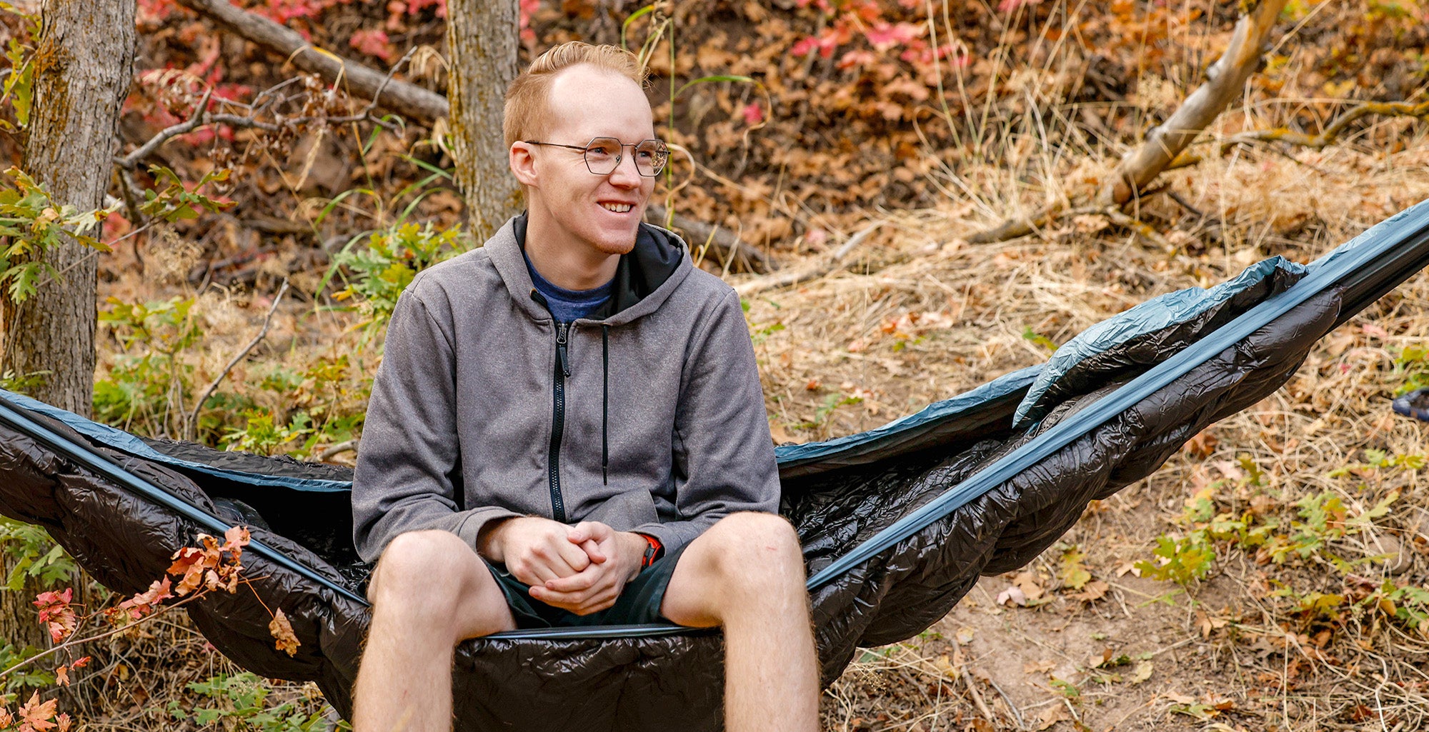 man sits in evolution sleeping bag hammock